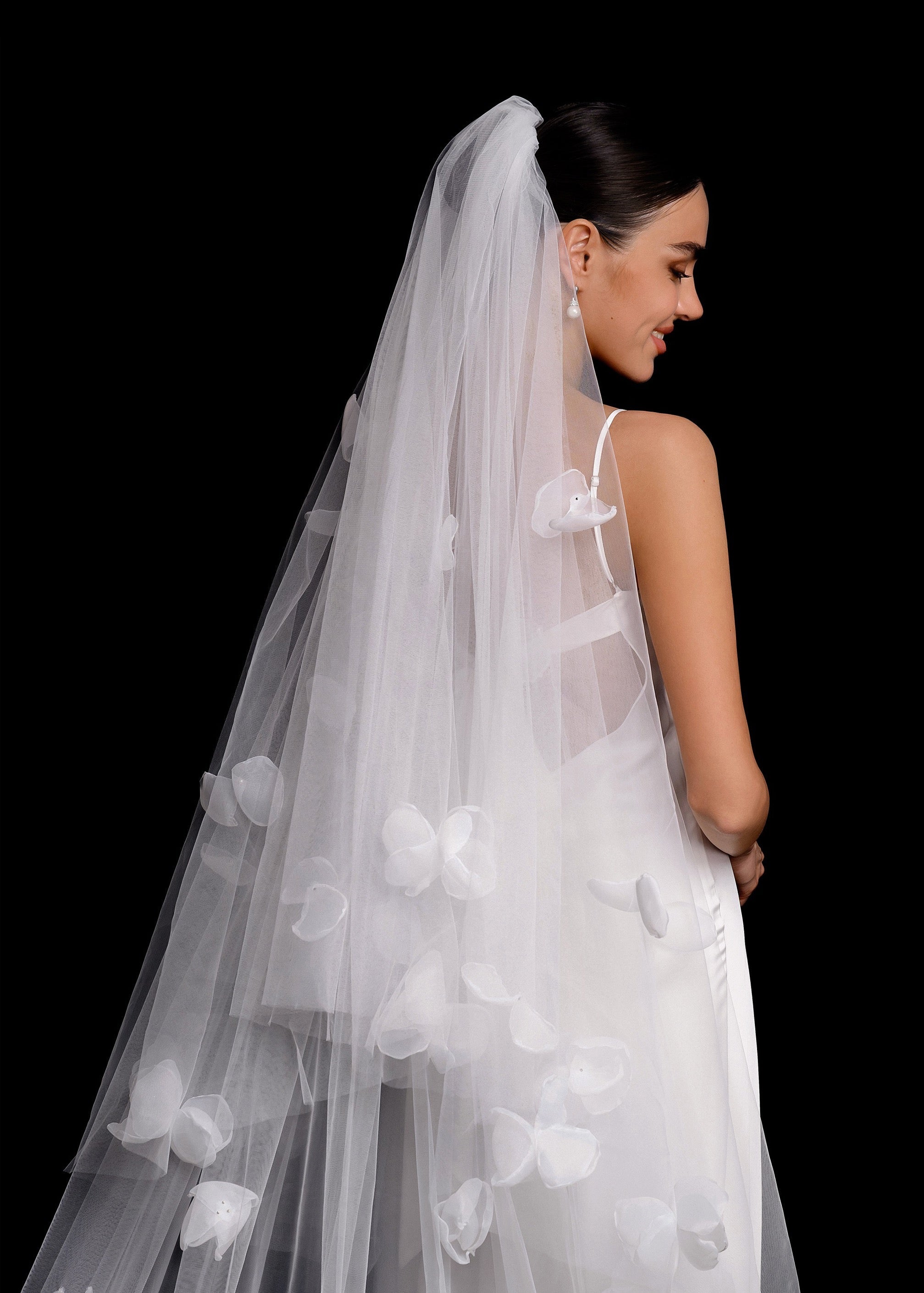 Bride wearing a floral veil against a black background