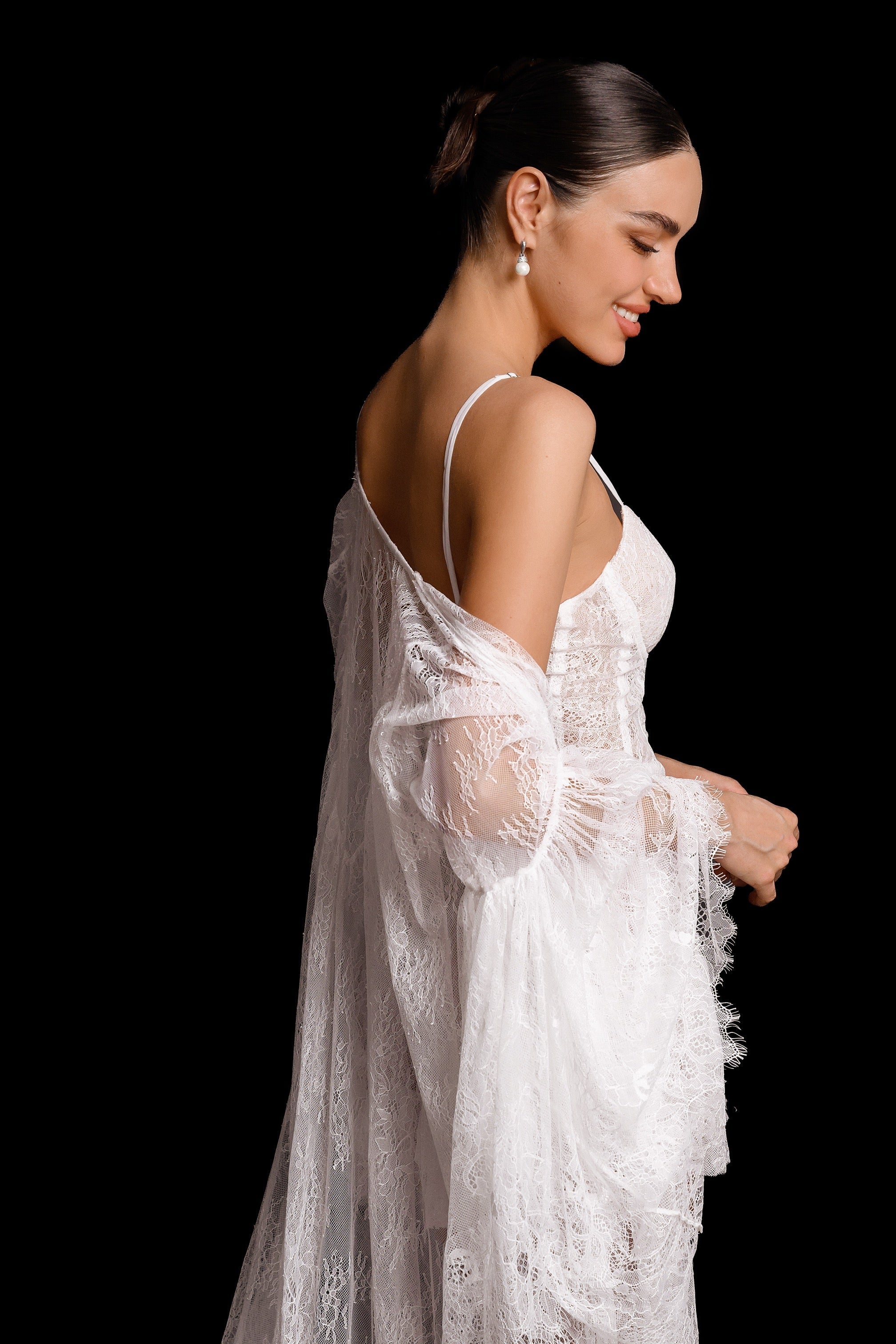 Woman wearing a white lace robe against a black background