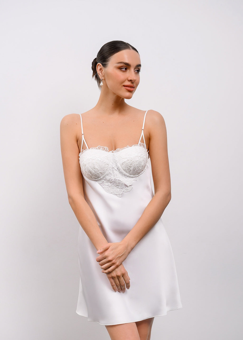 Woman wearing a white lace nightgown against a plain background