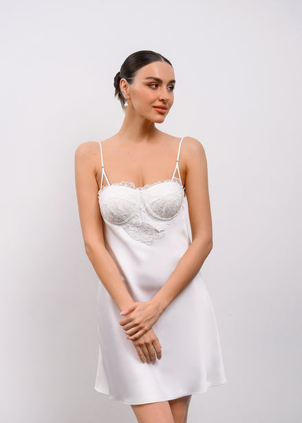 Woman wearing a white lace nightgown against a plain background