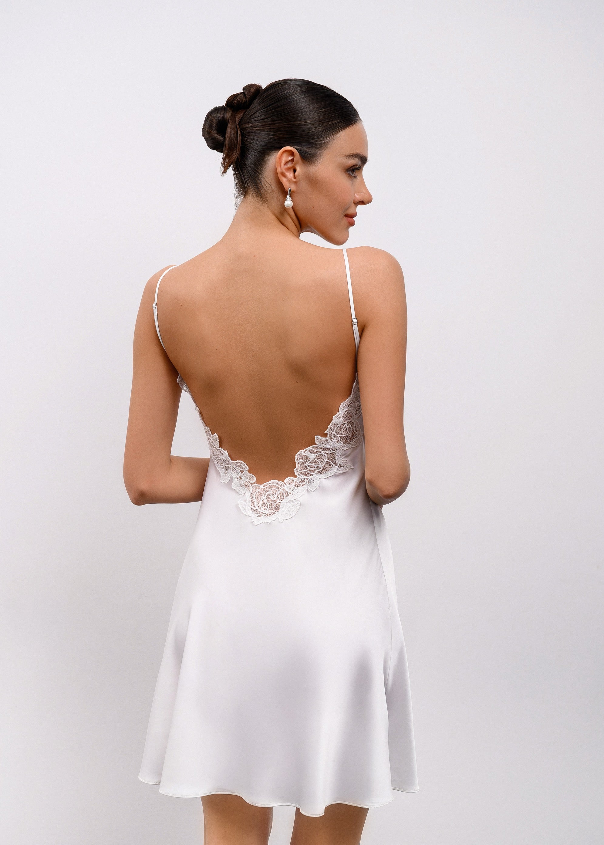 Woman wearing a white lace nightgown against a plain background