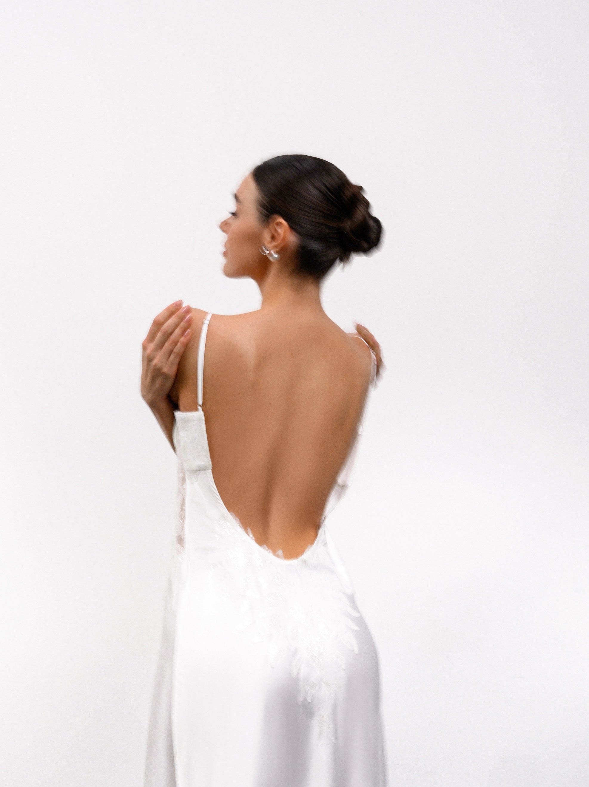 Woman wearing a white dress with an open back on a light gray background