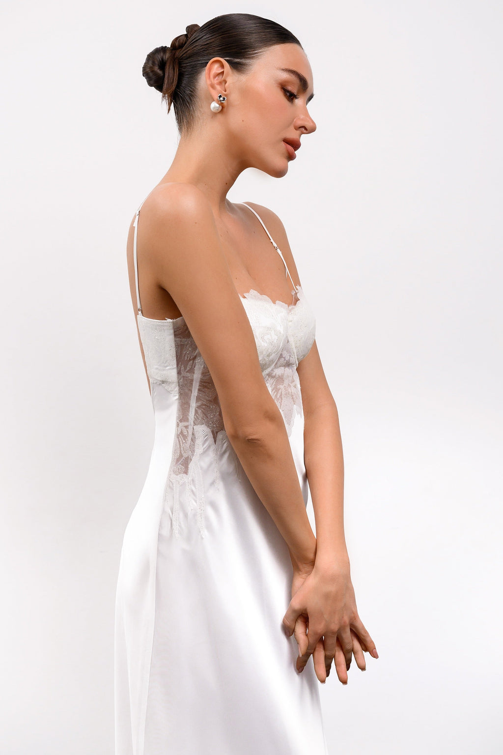 Woman wearing a white dress with thin straps on a plain background