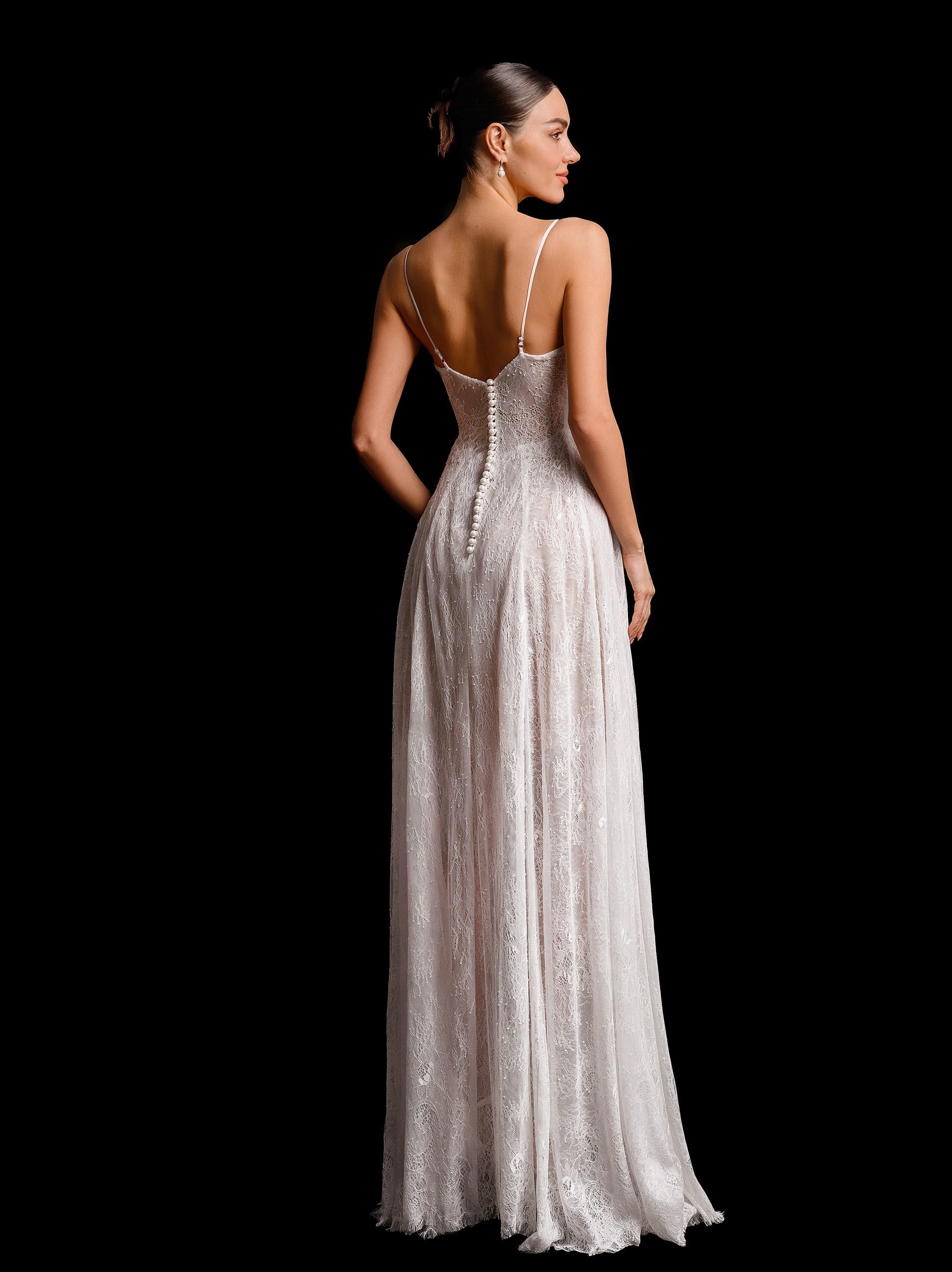 Woman wearing a long, elegant dress with thin straps on a black background