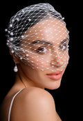 Woman wearing a birdcage veil with pearls on a black background