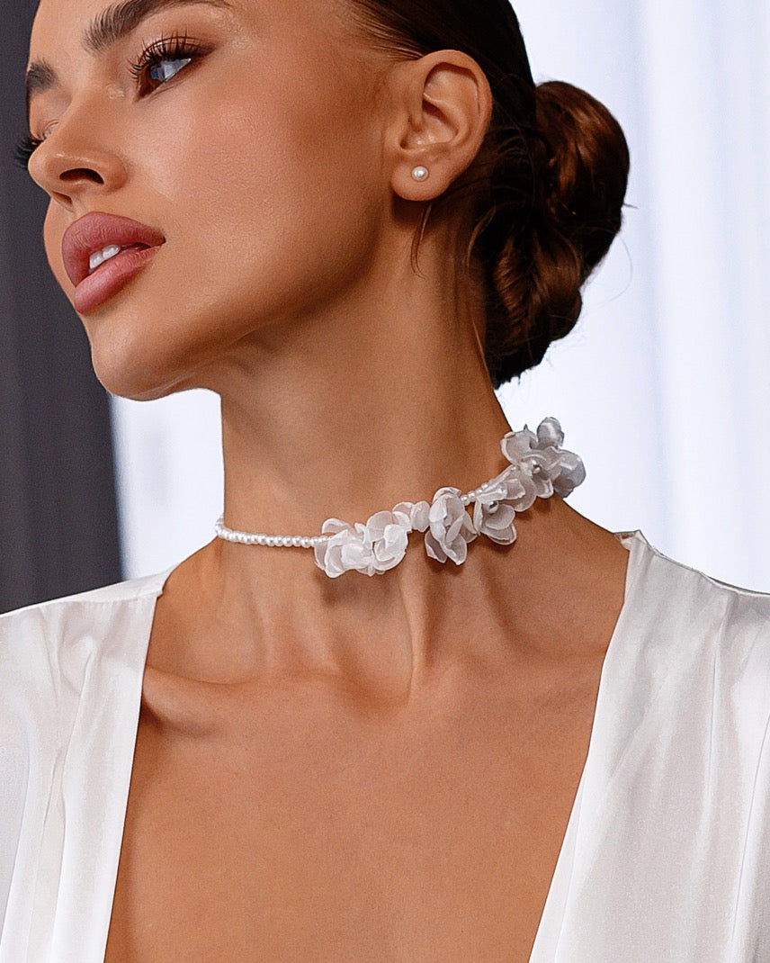 Close-up of a woman wearing a delicate floral necklace with a blurred background